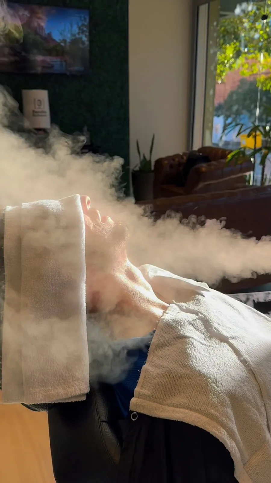 Cliente relaxando com toalha quente durante o atendimento na Bendita Barbearia